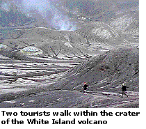 Two tourists walk within the crater of the White Island volcano