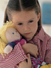A young girl hugging a doll and looking scared