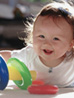 A happy infant playing independently with a ring toy